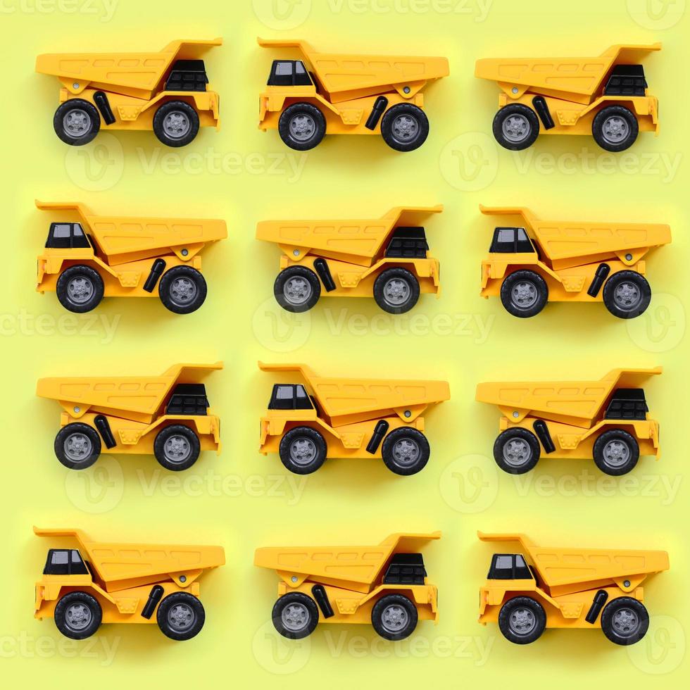 De nombreux petits camions jouets jaunes sur fond de texture de papier de couleur jaune pastel de mode dans un concept minimal photo