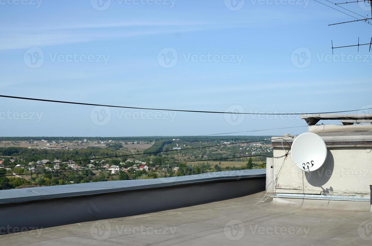 antenne parabolique blanche avec trois convertisseurs montés sur un mur en béton sur le toit d'un immeuble résidentiel. Télévision par satellite photo