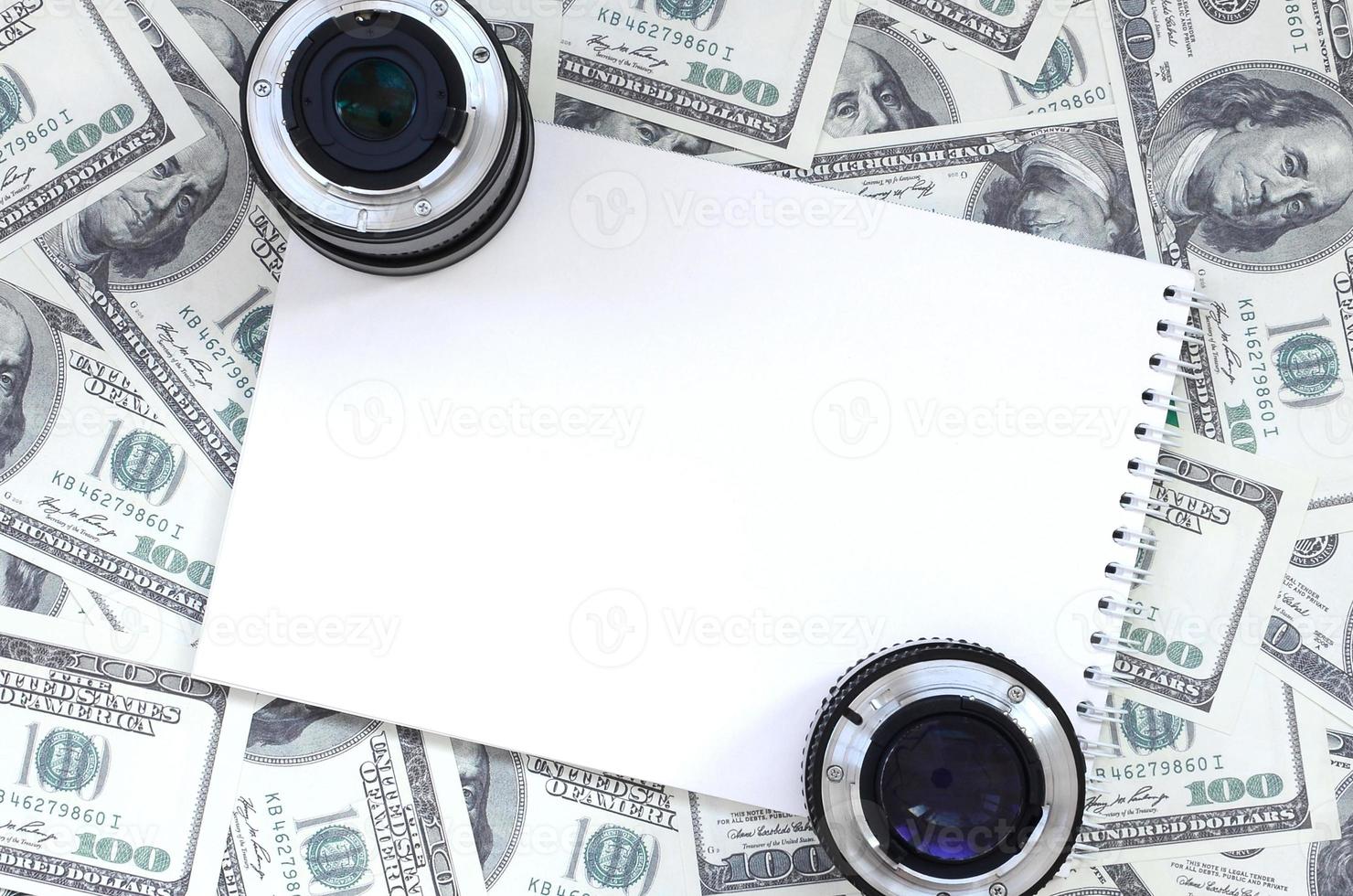 deux lentilles photographiques et un cahier blanc se trouvent sur le fond de beaucoup de billets d'un dollar. espace pour le texte photo