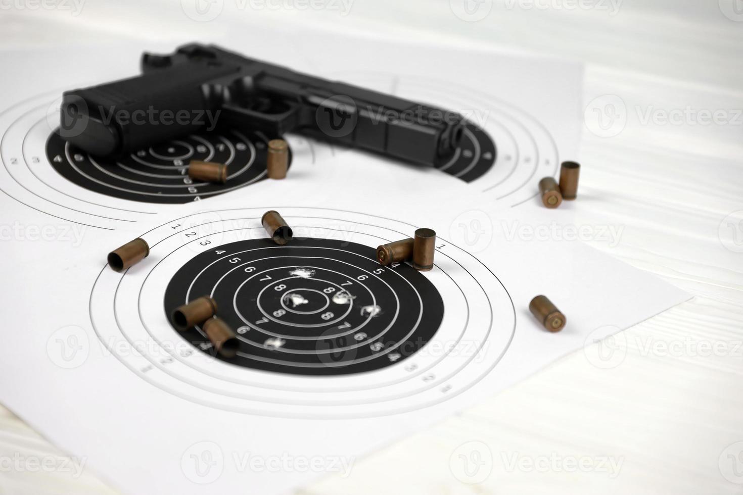 pistolet et de nombreuses balles tirant des cibles sur une table blanche dans un polygone de champ de tir. formation à la visée et au tir photo