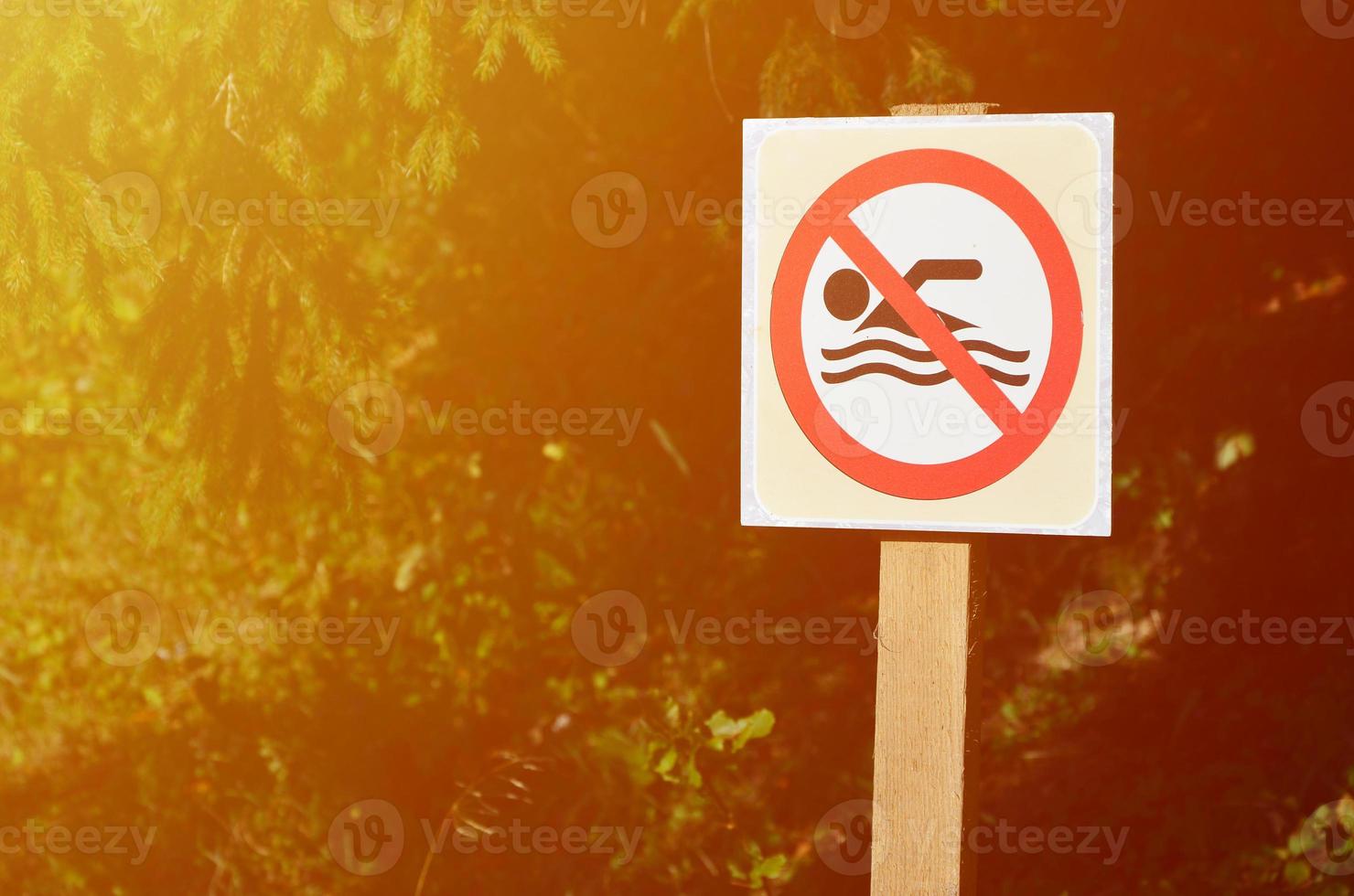 un pilier avec un panneau indiquant une interdiction de baignade. le signe montre une personne flottante barrée photo