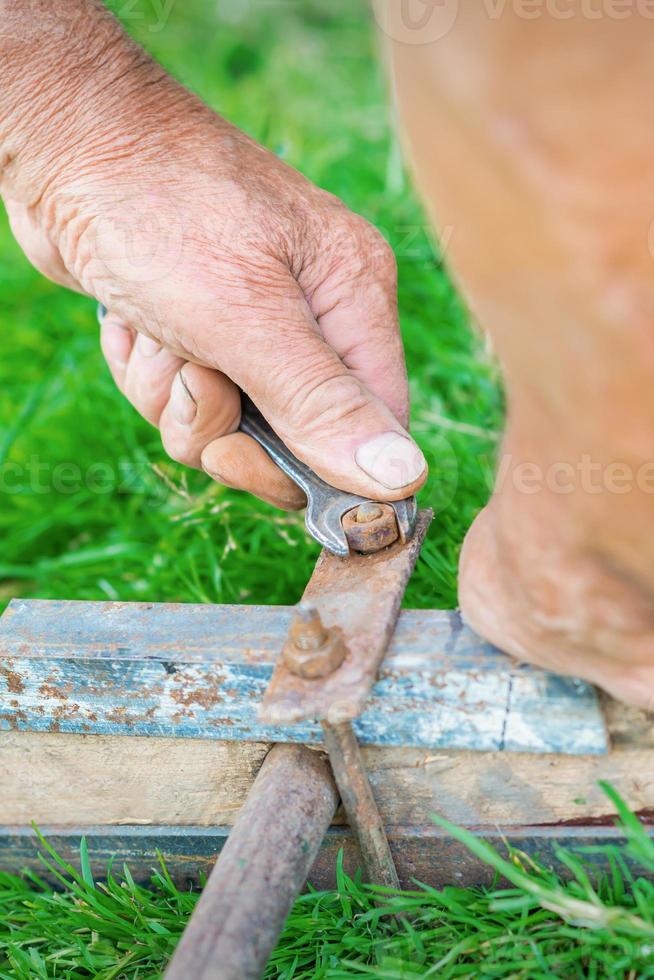 Un vieil homme tord l'écrou à l'aide d'une clé photo