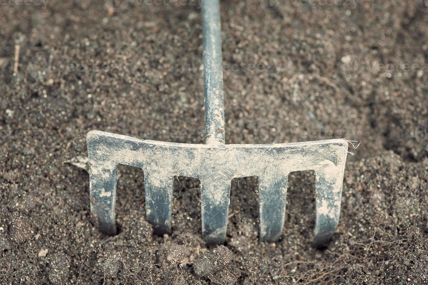 gros plan de cultivateur de jardin en métal sale utilisé sur le fond du sol. photo