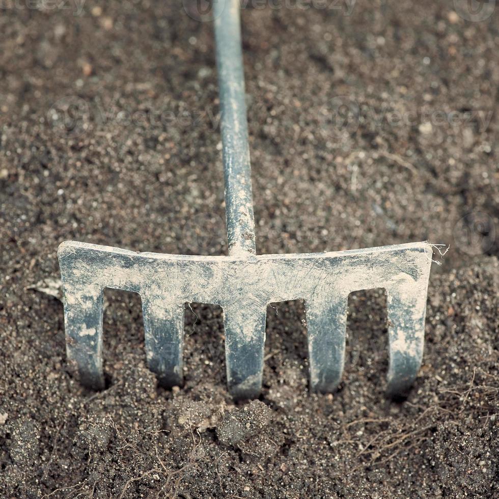 gros plan de cultivateur de jardin en métal sale utilisé sur le fond du sol. photo