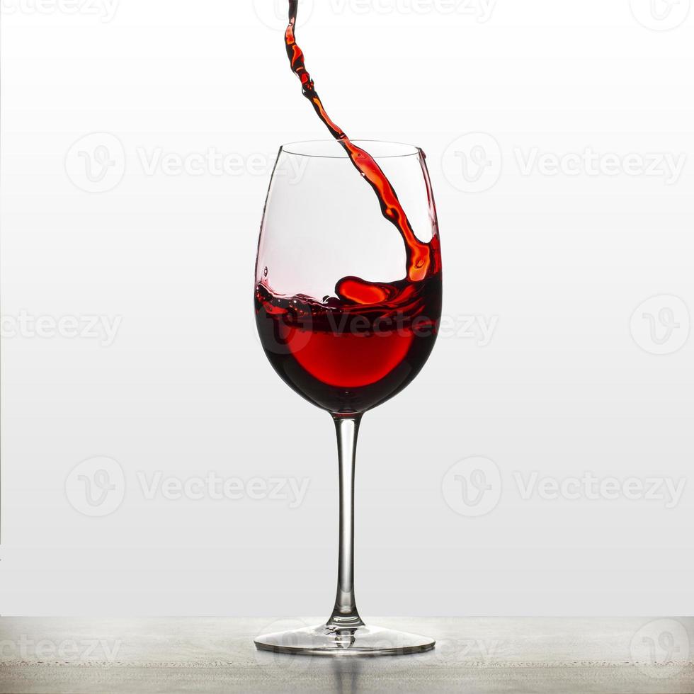 une éclaboussure de vin rouge dans un verre à vin. éclaboussures de vin. boire de l'eau. de l'alcool. isolé sur fond photo