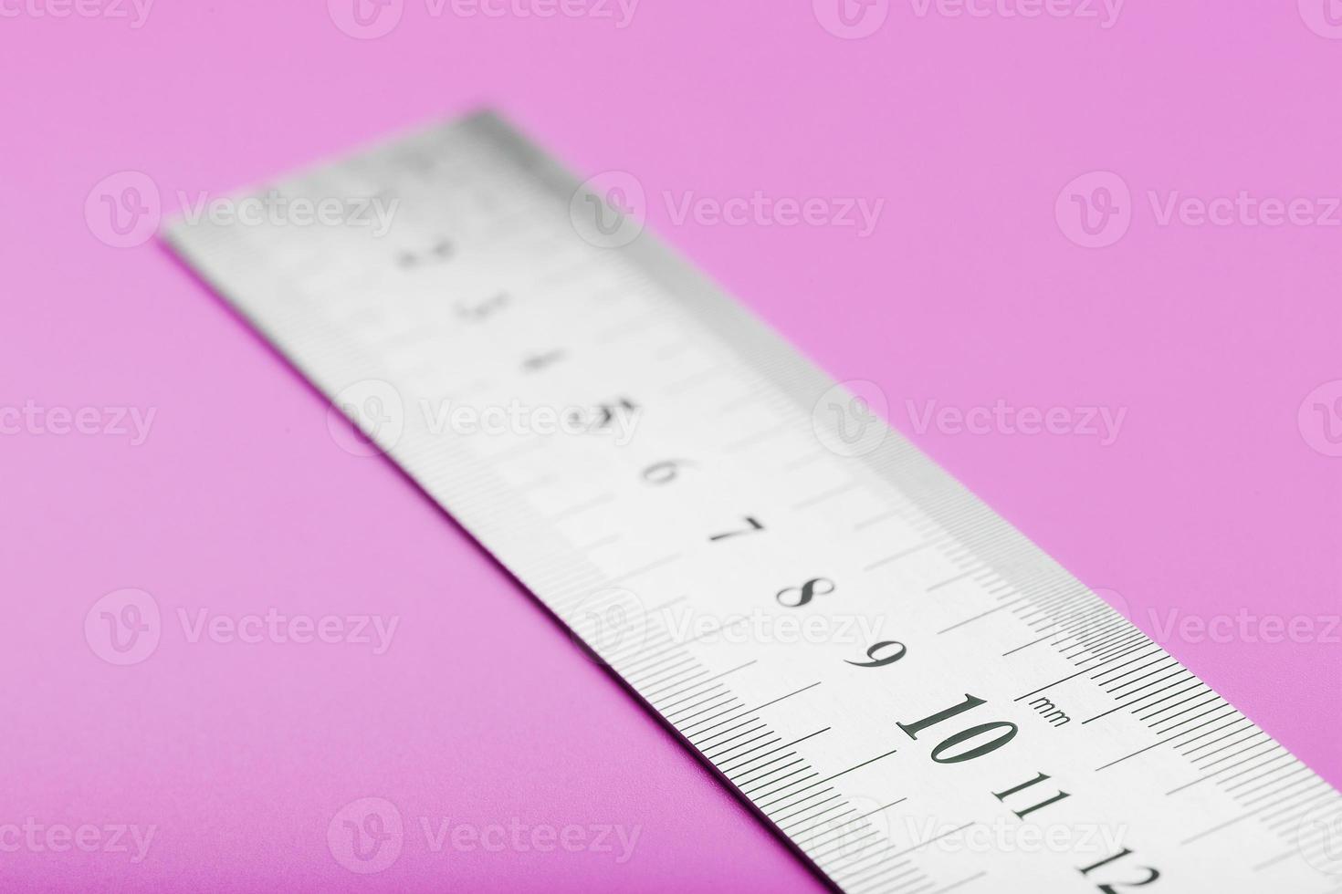 règle en métal sur un gros plan de fond rose avec une copie de la place pour votre texte. photo