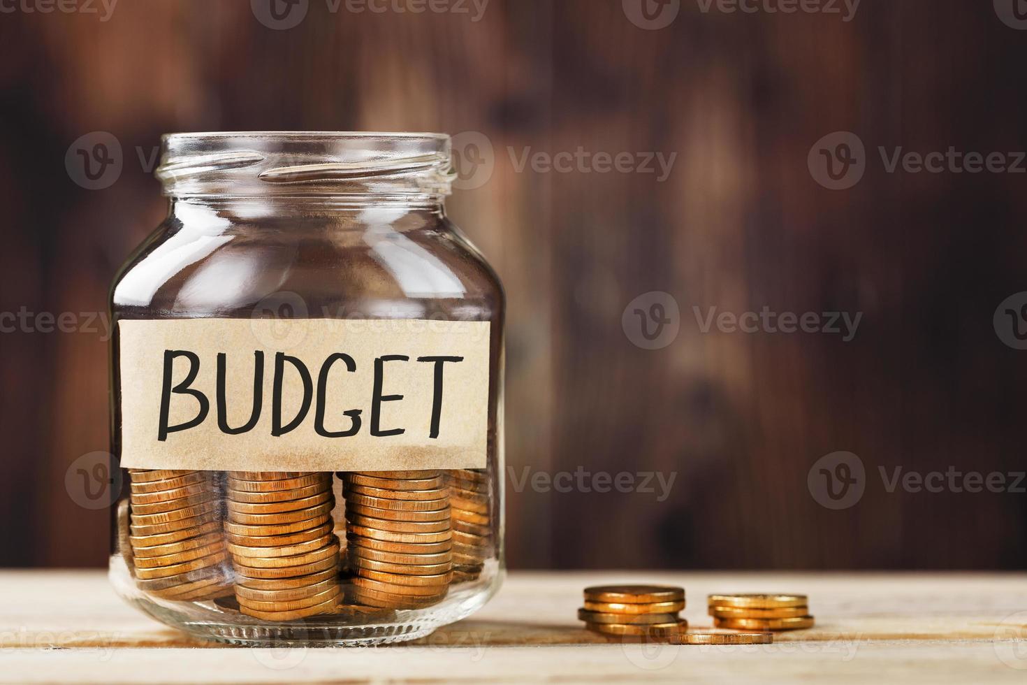 bocal en verre avec de l'argent et un autocollant avec les mots budget, sur une table en bois. photo