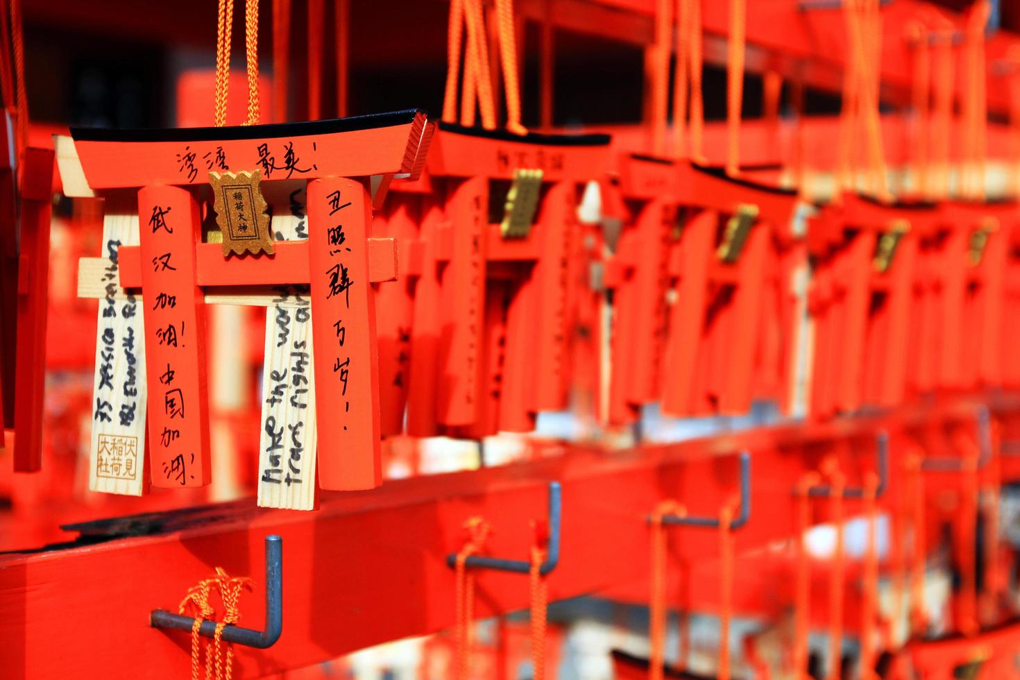 kyoto, japon - 25 février 2020 de nombreuses petites portes torii accrochées à un cintre en bois rouge au sanctuaire fushimi inanari. les gens écrivent des bénédictions sur des amulettes et prient pour être vrais. photo