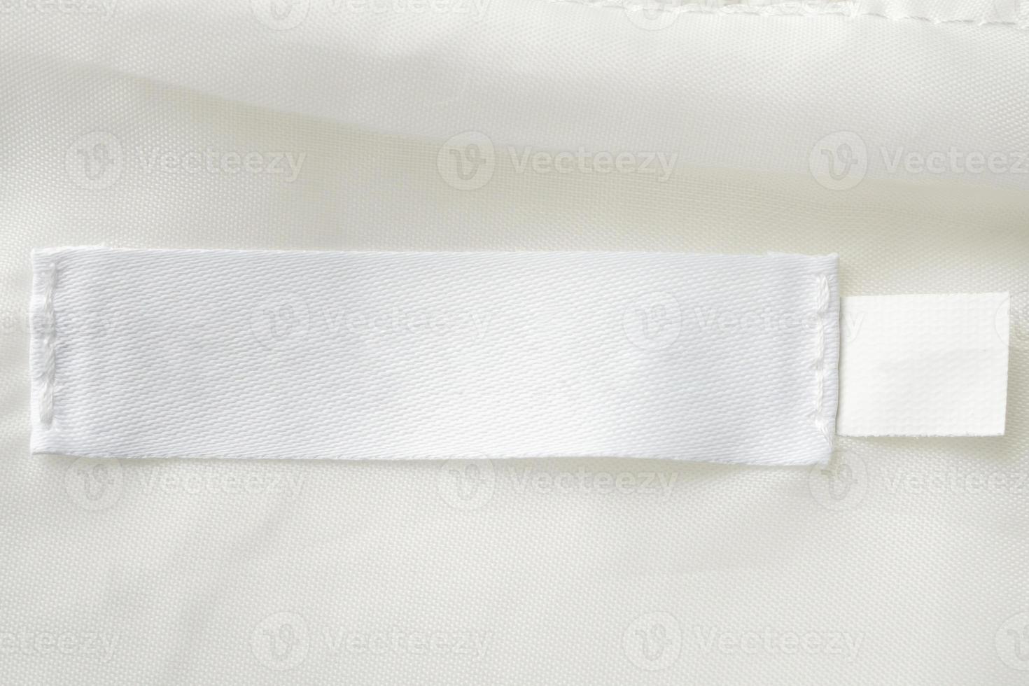 étiquette de vêtements de soin de lessive blanche vierge sur fond de texture de tissu photo