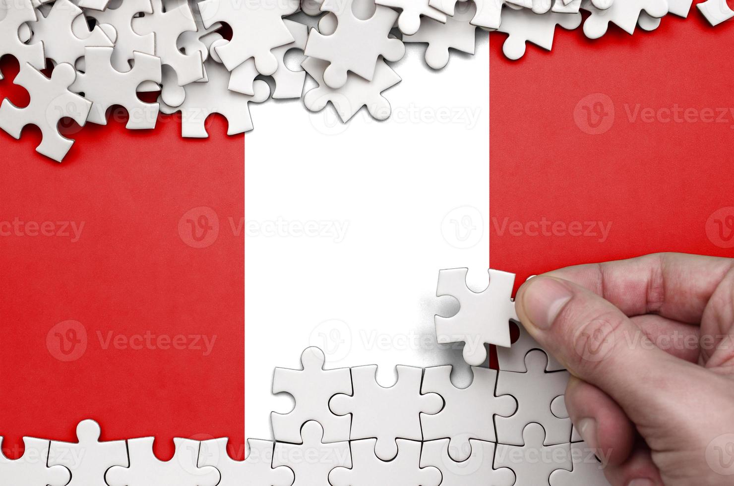 le drapeau du pérou est représenté sur une table sur laquelle la main humaine plie un puzzle de couleur blanche photo