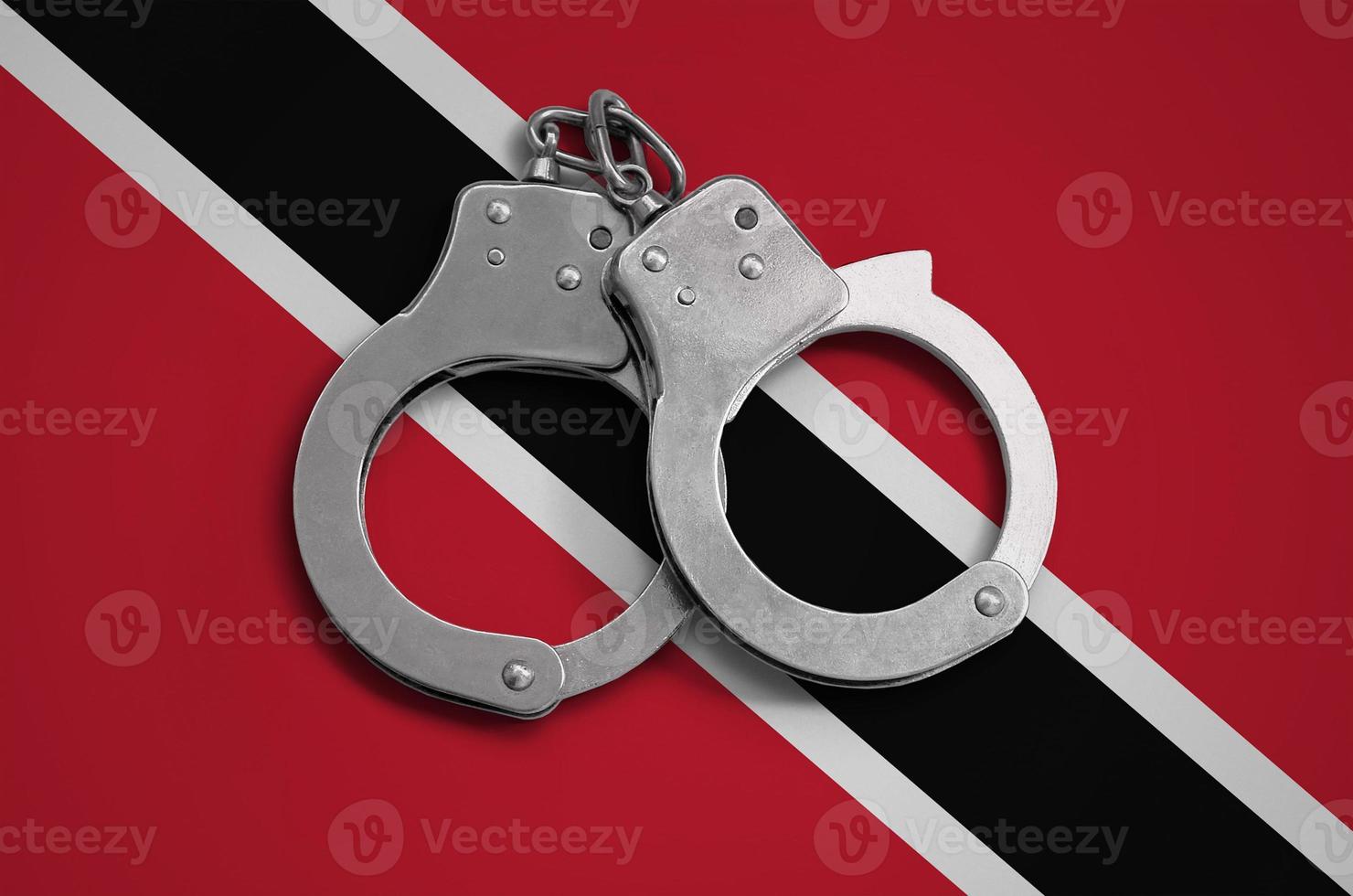 drapeau de trinité-et-tobago et menottes de police. le concept de respect de la loi dans le pays et de protection contre le crime photo