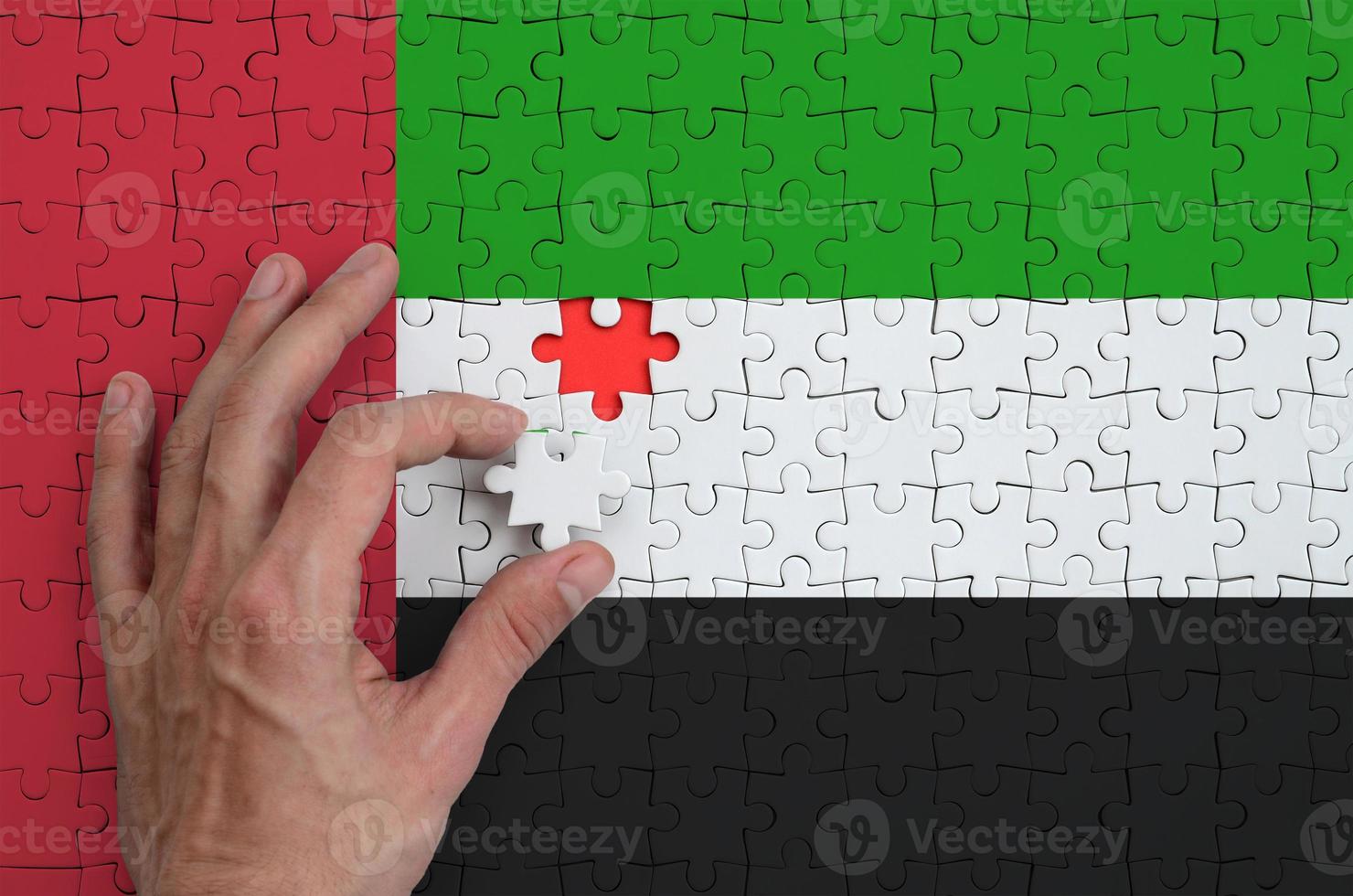 le drapeau des émirats arabes unis est représenté sur un puzzle, que la main de l'homme complète pour se plier photo