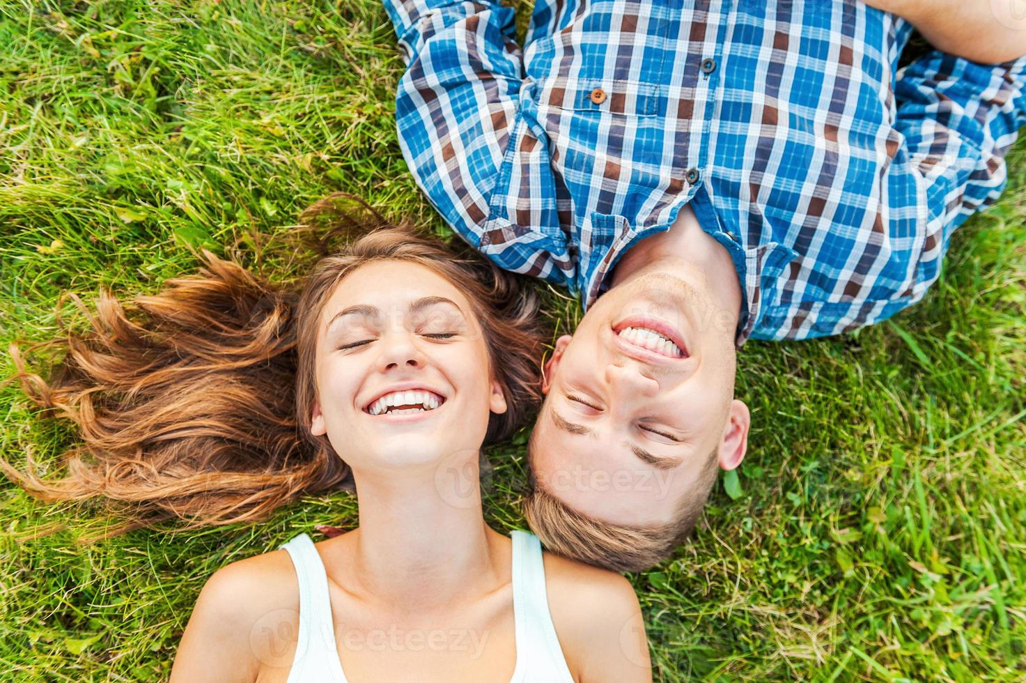 plaisirs de l'été. vue de dessus d'un jeune couple amoureux couché ensemble sur l'herbe et souriant photo