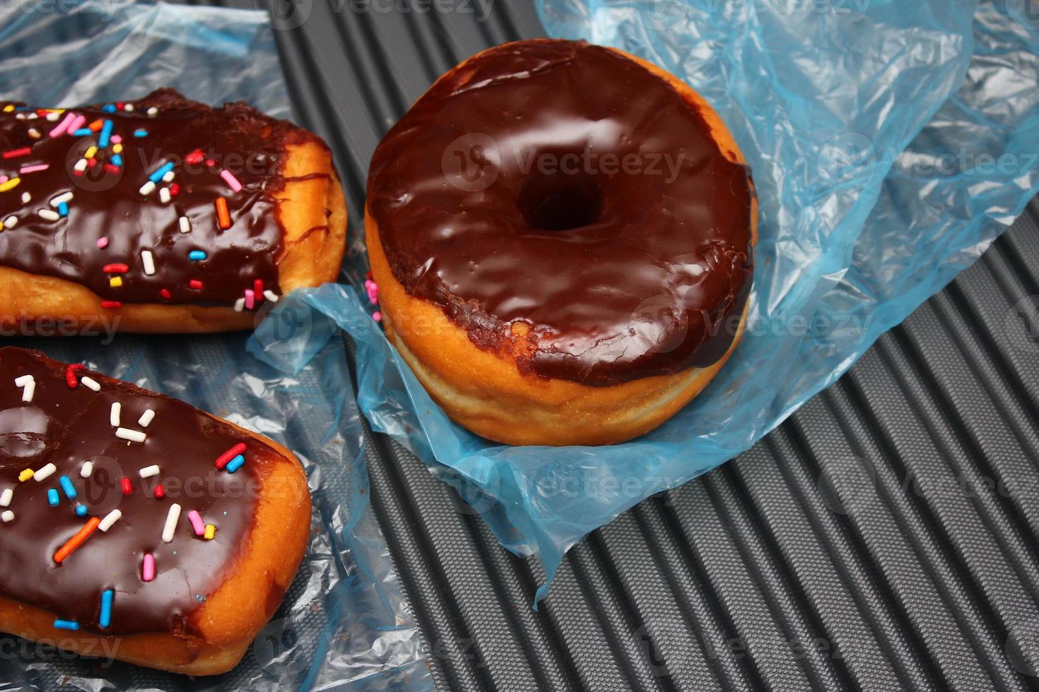 beignets au chocolat et barres de beignets au chocolat garnis de flocons de sucre multicolores. posé sur un sol en aluminium gris. photo