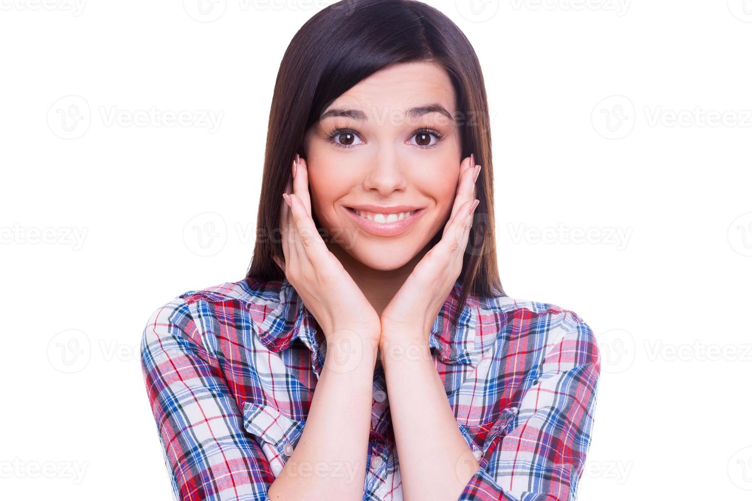 beauté surprise. belle jeune femme souriante regardant la caméra et touchant son visage avec les mains en se tenant debout isolé sur blanc photo