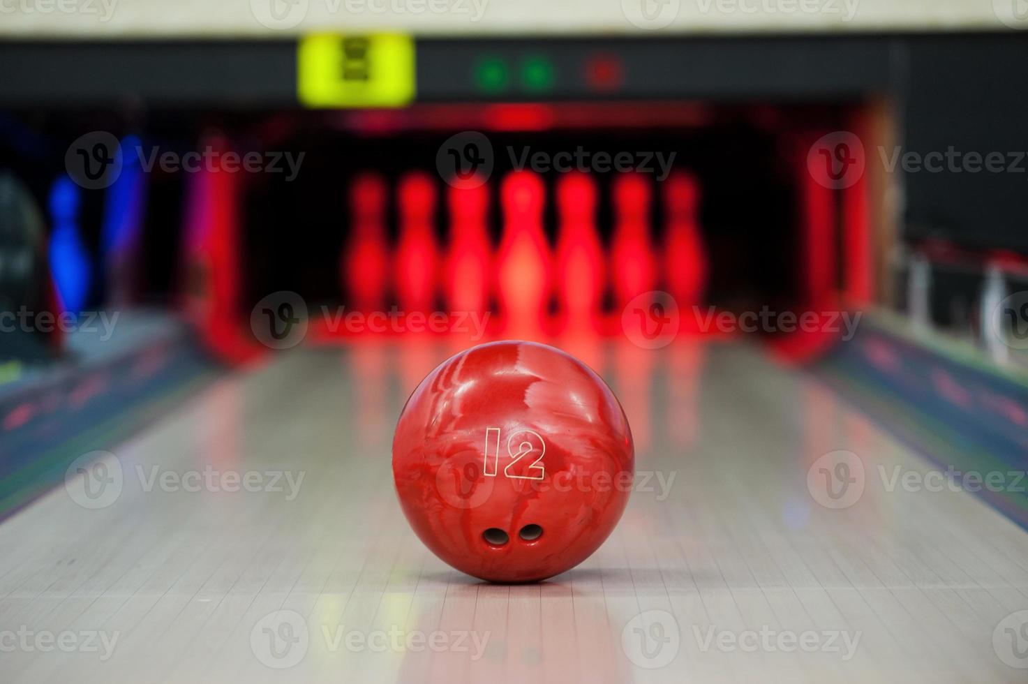 atteindre le but. gros plan d'une boule de bowling rouge vif roulant le long d'une piste de bowling photo