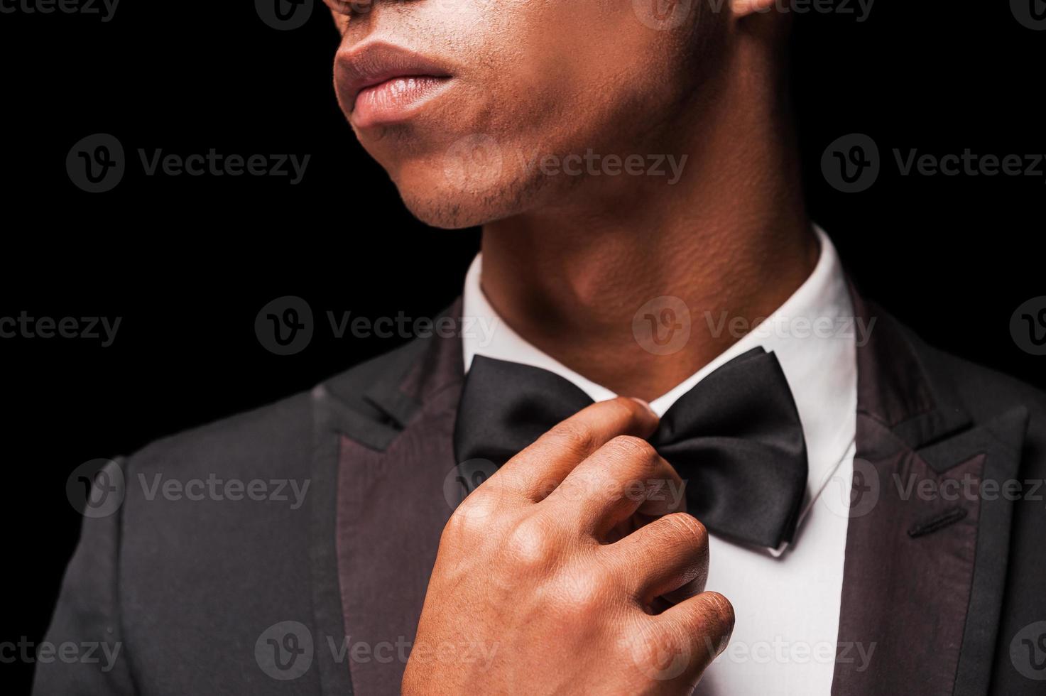 remettre le nœud papillon au goût du jour. jeune homme afro-américain à la mode corrigeant son noeud papillon photo
