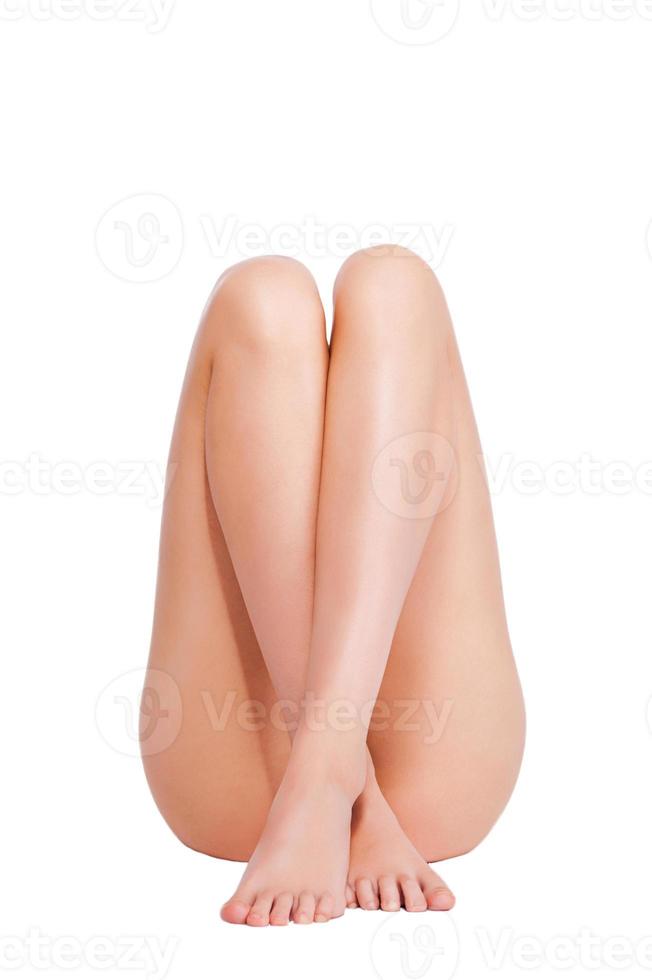 jambes parfaites. belle femme gardant ses jambes croisées et ses chevilles en position couchée sur fond blanc photo