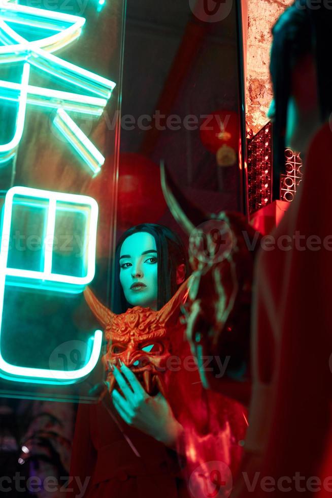 anime femme en costume rouge avec coupe de cheveux courte, cheveux noirs. une fille tueuse dans une veste rouge avec un masque japonais rouge. portrait beauté photo