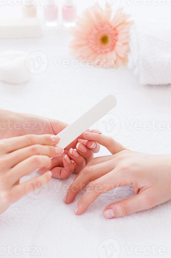 polissage des ongles féminins. gros plan d'une esthéticienne polissant les ongles d'une cliente photo