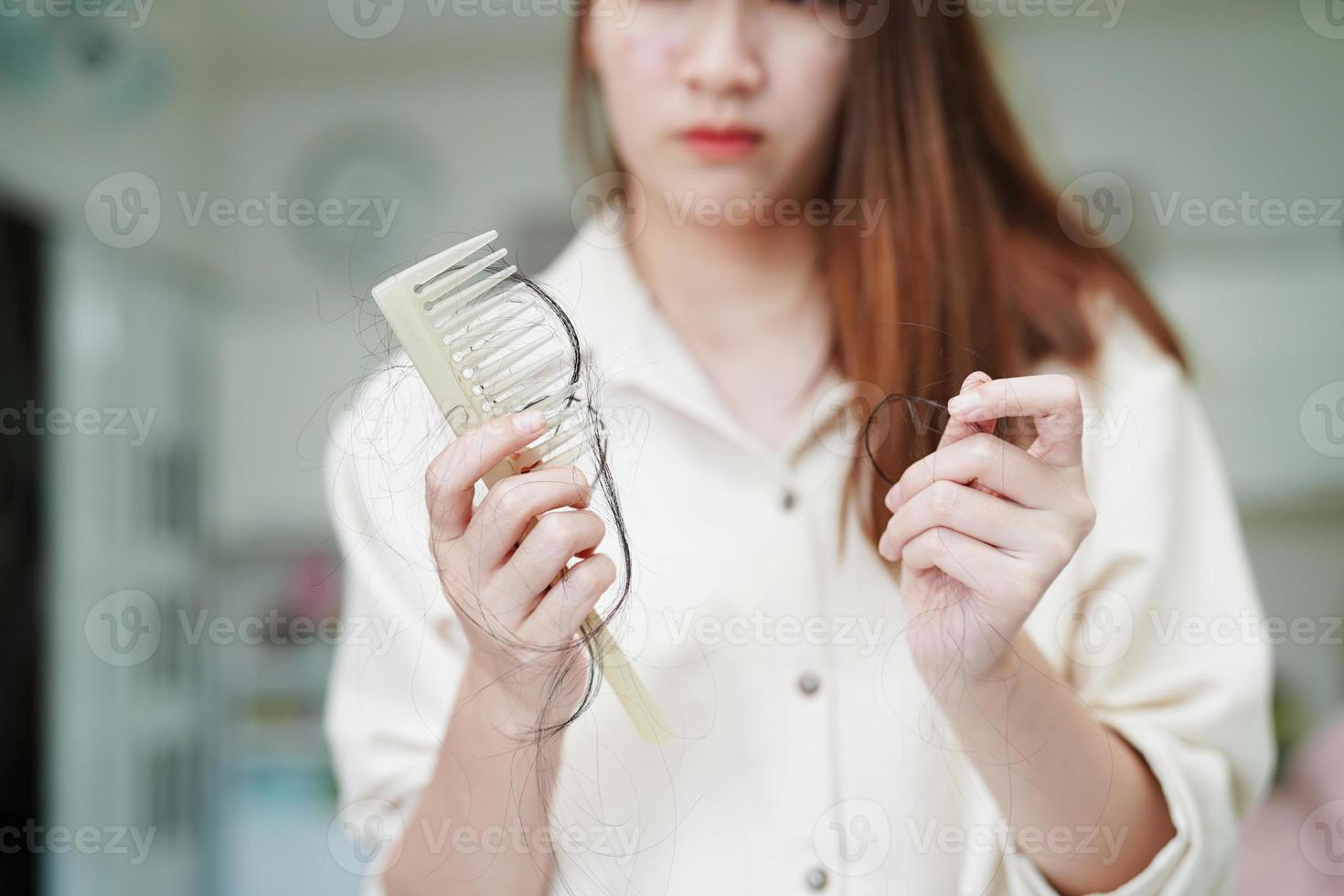 une femme asiatique a un problème avec la perte de cheveux longs attachée à la brosse à peigne. photo