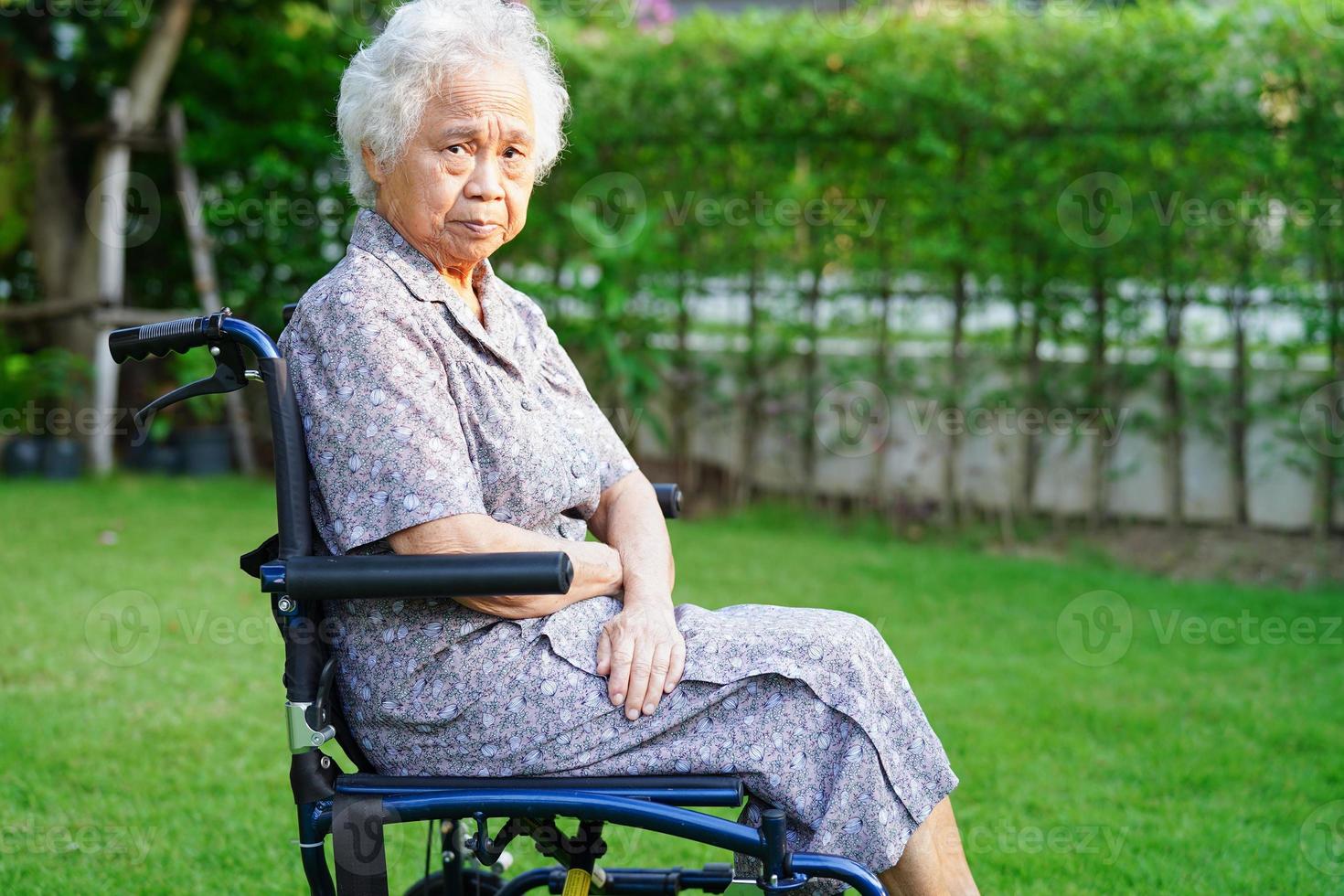 patient handicapé de femme âgée asiatique assis sur un fauteuil roulant dans le parc, concept médical. photo