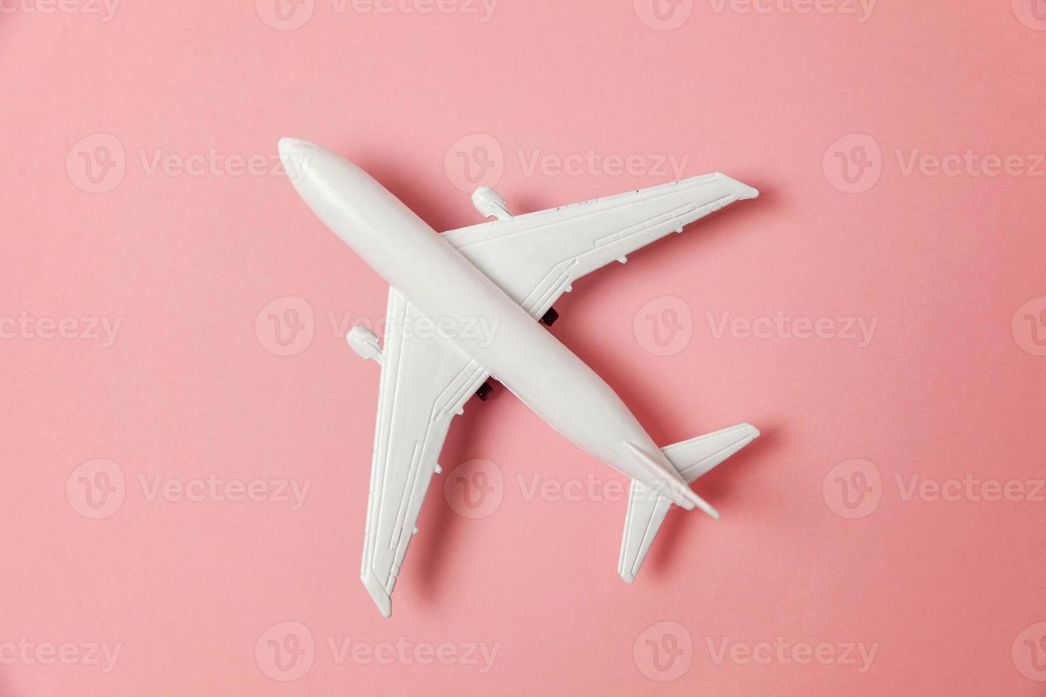 modèle de jouet miniature de conception simple à plat sur fond de papier coloré pastel rose tendance. voyage en avion vacances week-end d'été voyage d'aventure en mer concept de billet de voyage. photo