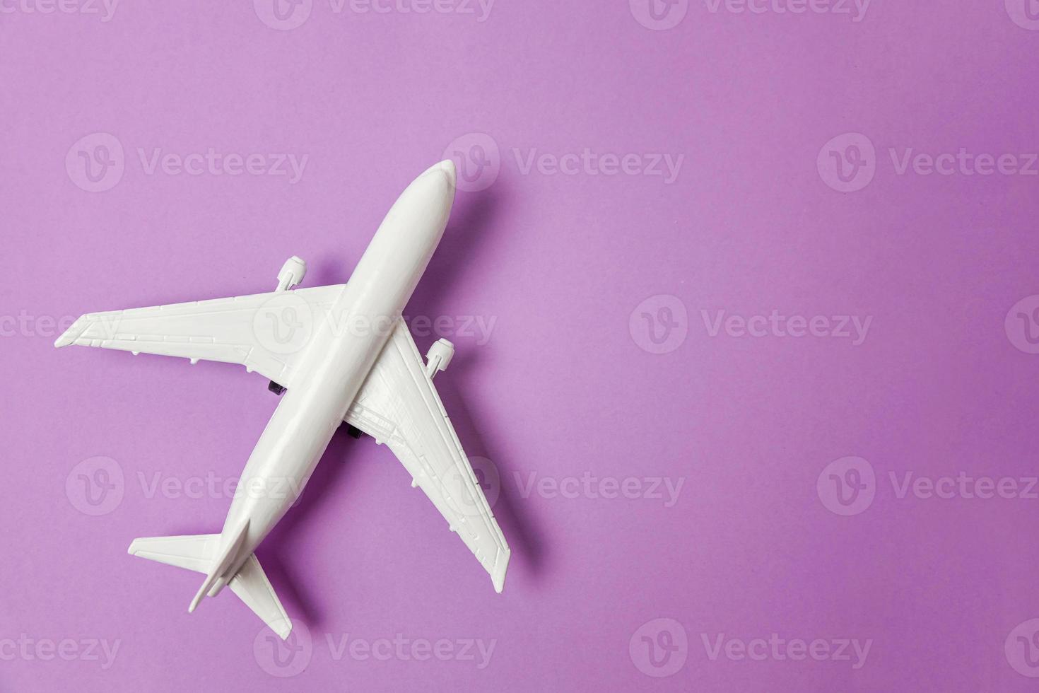 modèle de jouet miniature de conception simple à plat sur fond de papier coloré pastel violet violet violet. voyage en avion vacances week-end d'été voyage d'aventure en mer concept de billet de voyage. photo