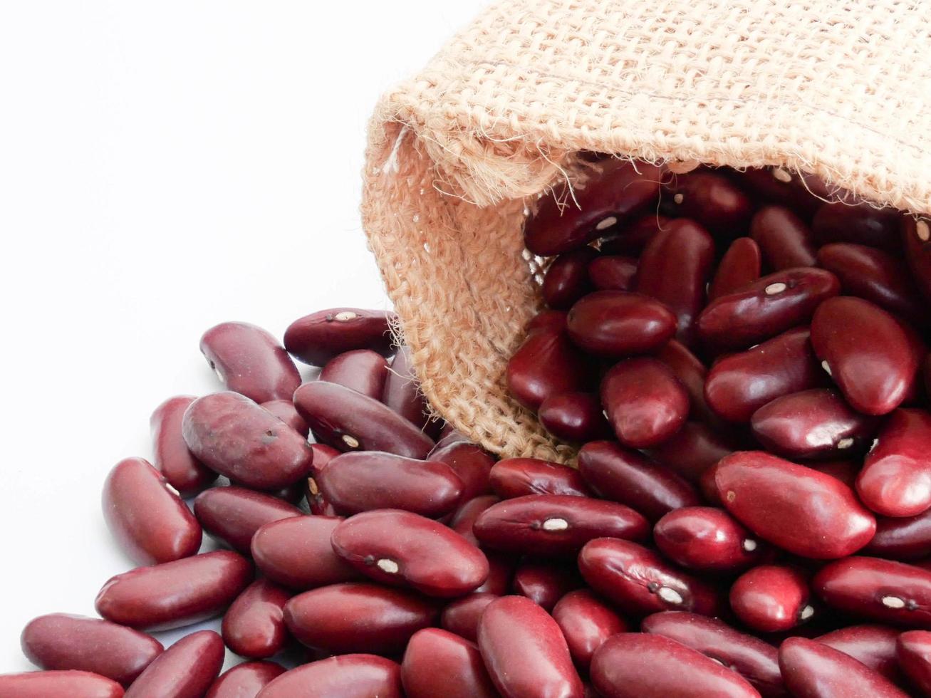 gros plan de haricots rouges dans un sac de chanvre sur fond blanc. photo