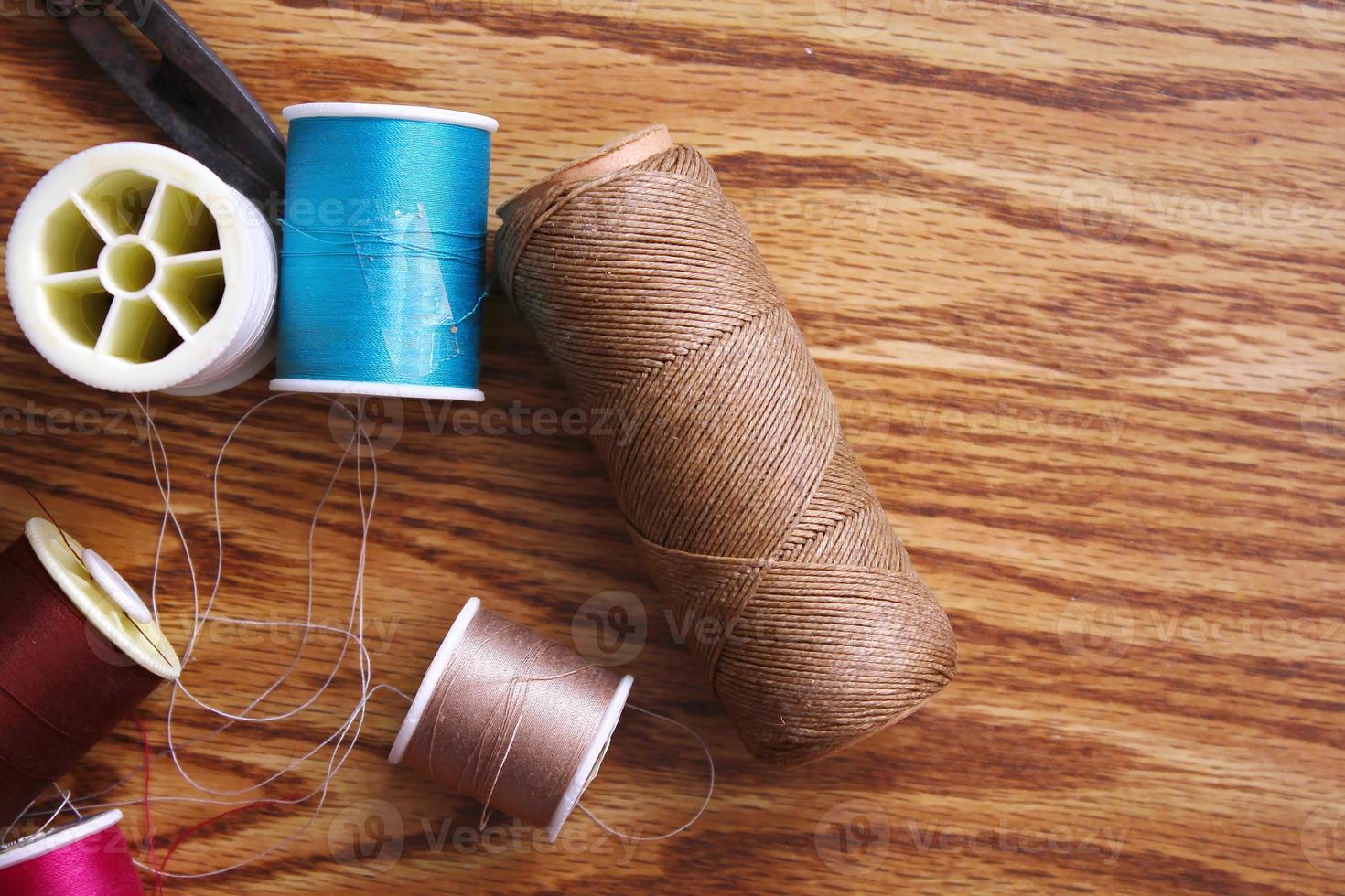 fils multicolores et vieux ciseaux éparpillés sur une table en bois, ciseaux rétro, mise à plat, espace de copie. photo