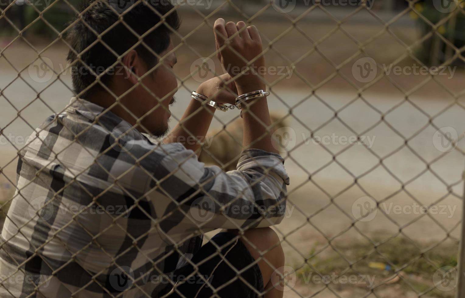 photo en gros plan des mains en prison poignée en treillis d'acier gère la cage en treillis d'acier, manque d'indépendance.