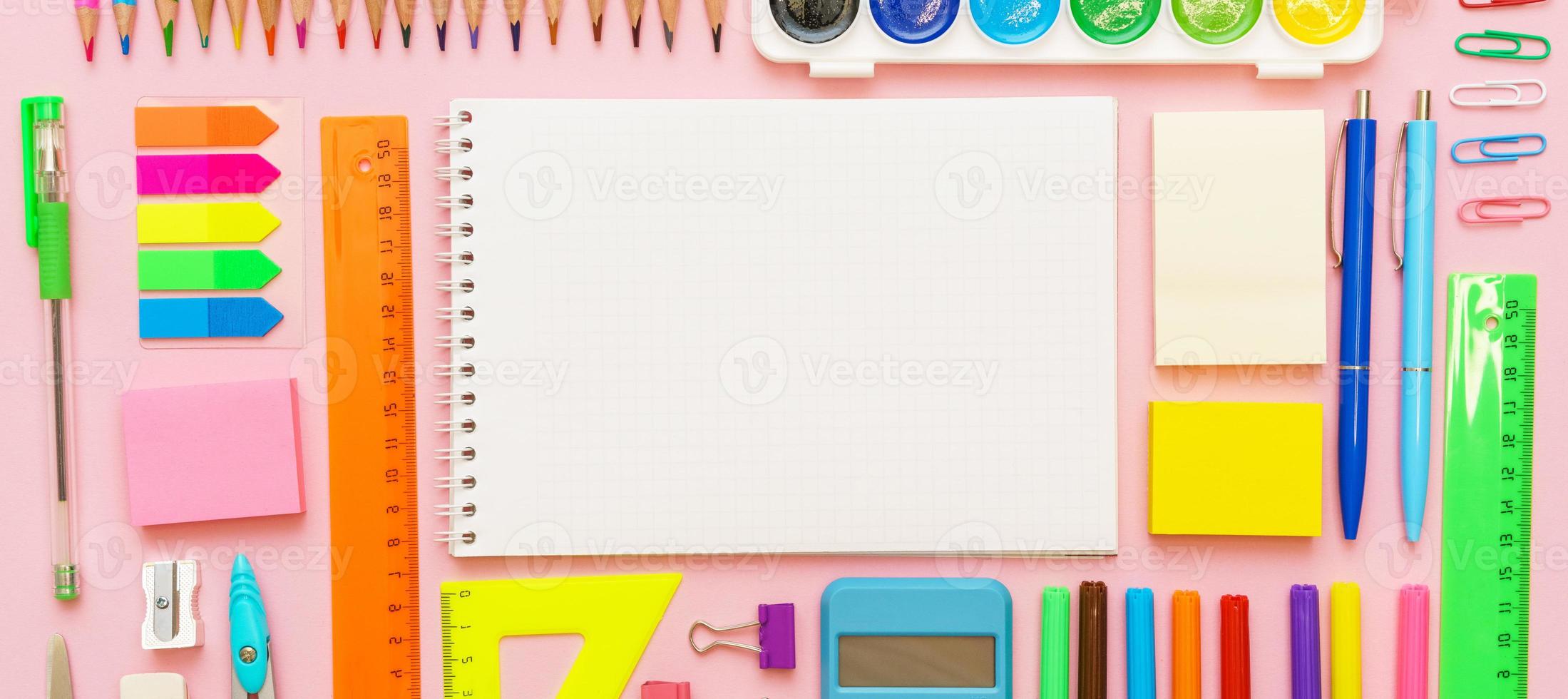 fournitures scolaires, papeterie sur fond rose. stylos crayons bloc-notes. mise à plat photo