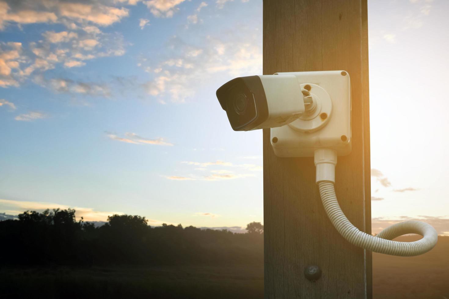 caméra de vidéosurveillance ip installée sur un poteau en bois à l'extérieur de la maison pour assurer la sécurité en surveillant via un téléphone mobile et d'autres appareils intelligents pour sauver la propriété et la vie humaine. photo