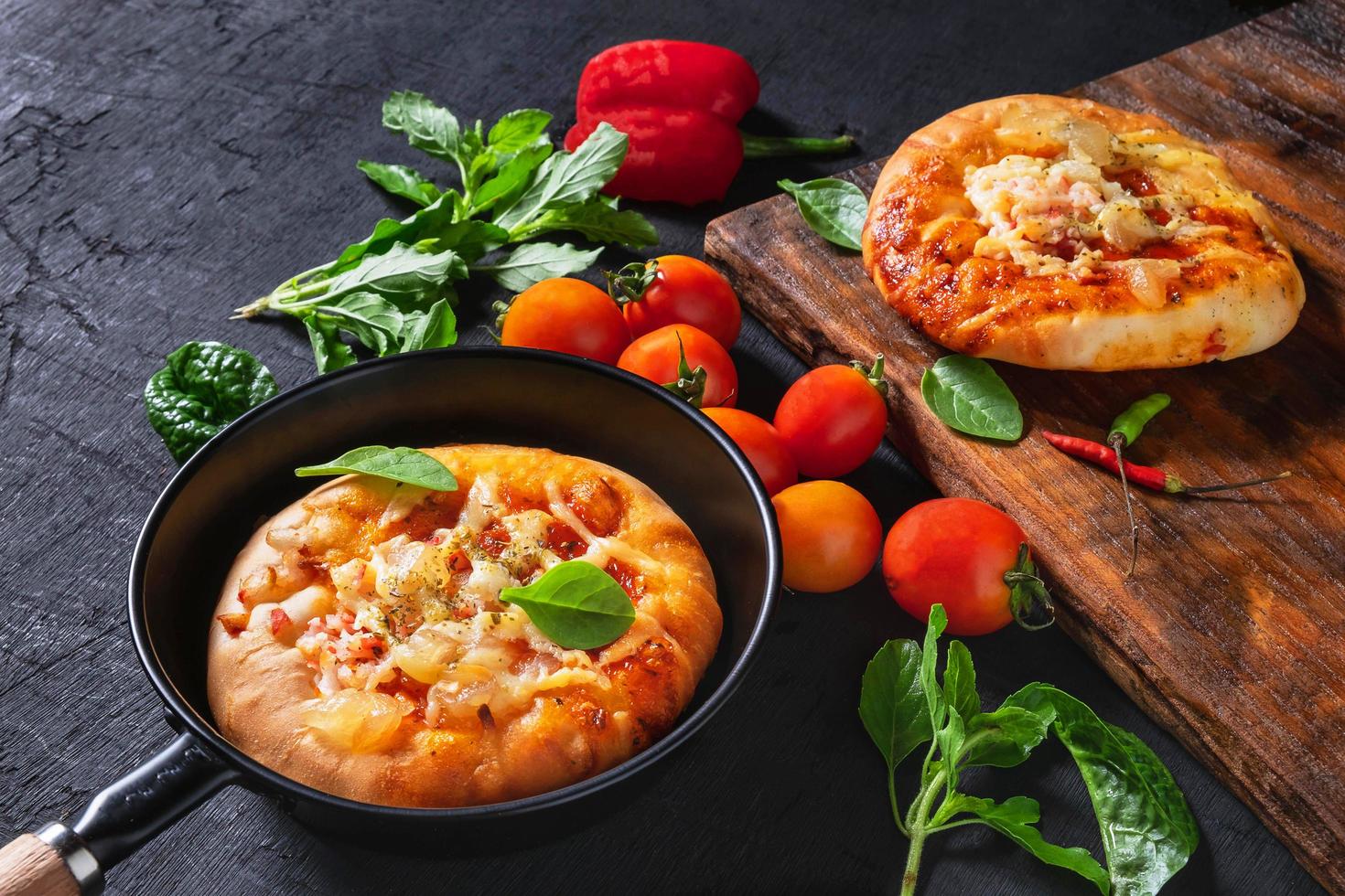 pizza dans une poêle et une autre sur un plateau en bois photo