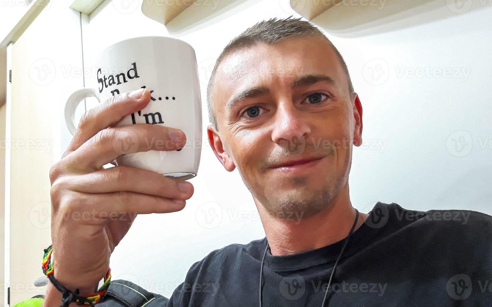 homme heureux buvant du café dans une tasse blanche le matin. photo