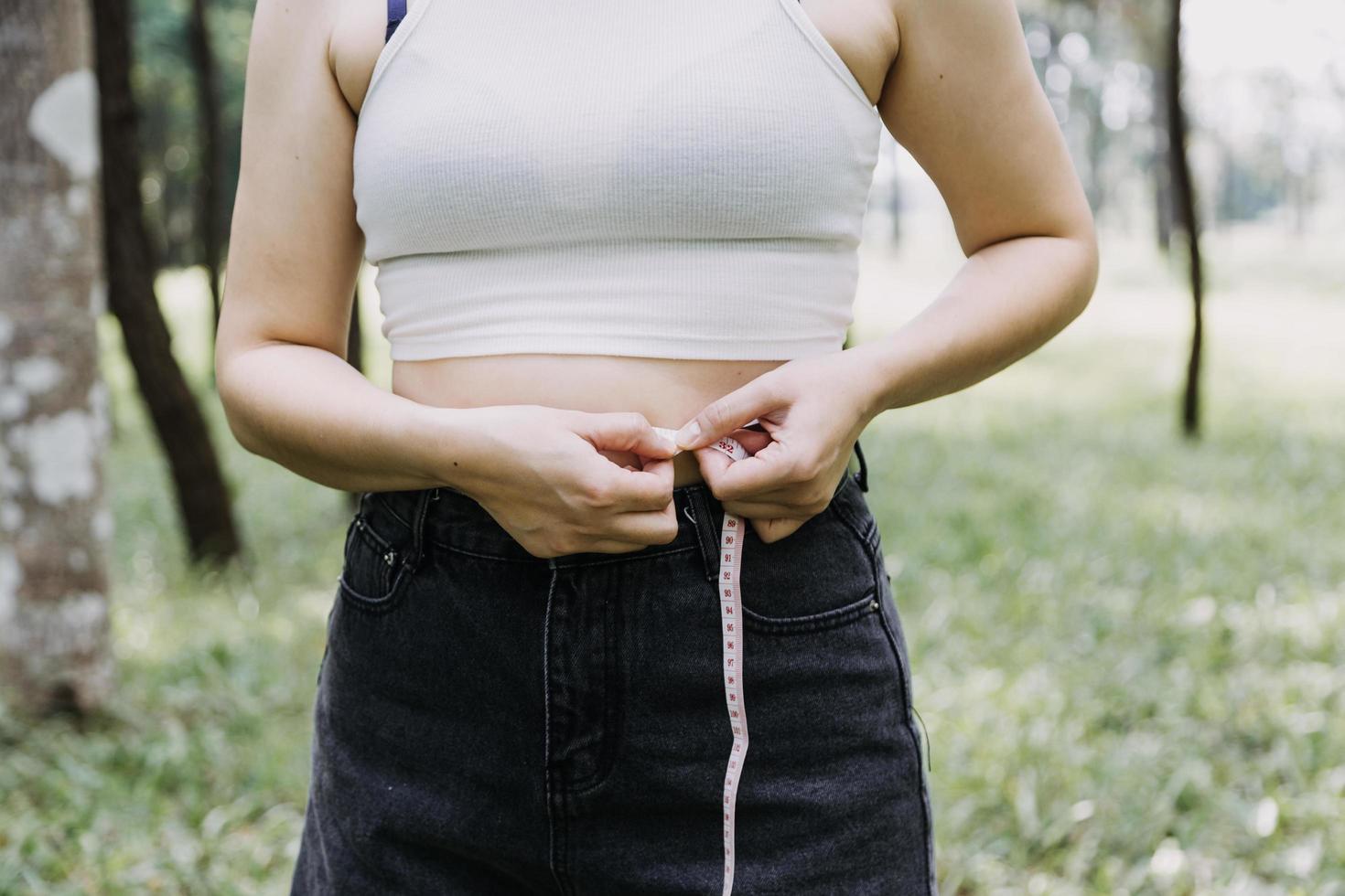 belle grosse femme avec ruban à mesurer, elle utilise sa main pour presser l'excès de graisse isolé sur fond blanc. elle veut perdre du poids, le concept de chirurgie et décomposer les graisses sous le photo