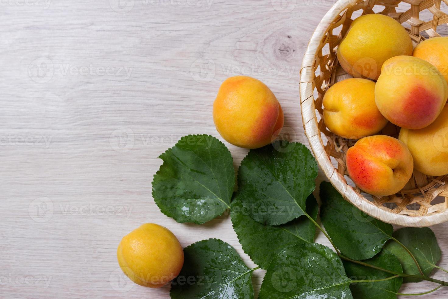 abricots frais dans le panier sur une table en bois photo