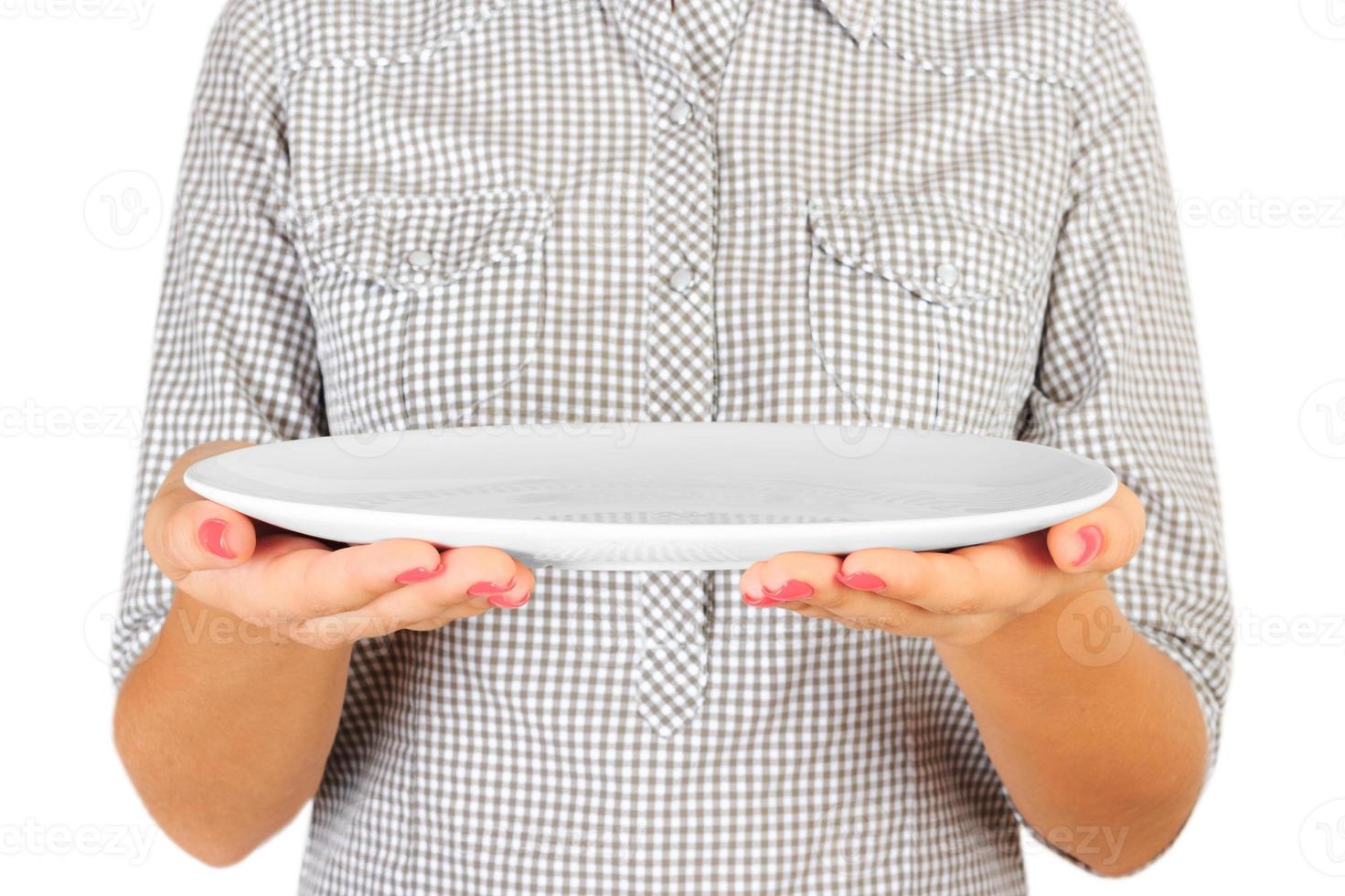 fille dans la chemise à carreaux tient une assiette blanche ronde vide devant elle. la main de la femme tient un plat vide pour vous desing. vue en perspective, isolé sur fond blanc photo