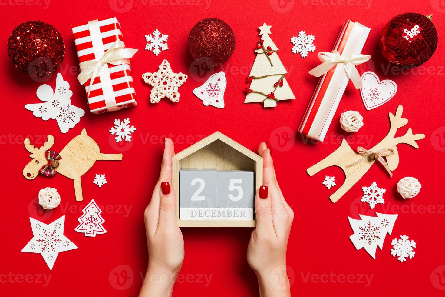 vue de dessus des mains féminines tenant le calendrier sur fond rouge. le vingt cinq décembre. décorations de vacances. notion de temps de noël photo