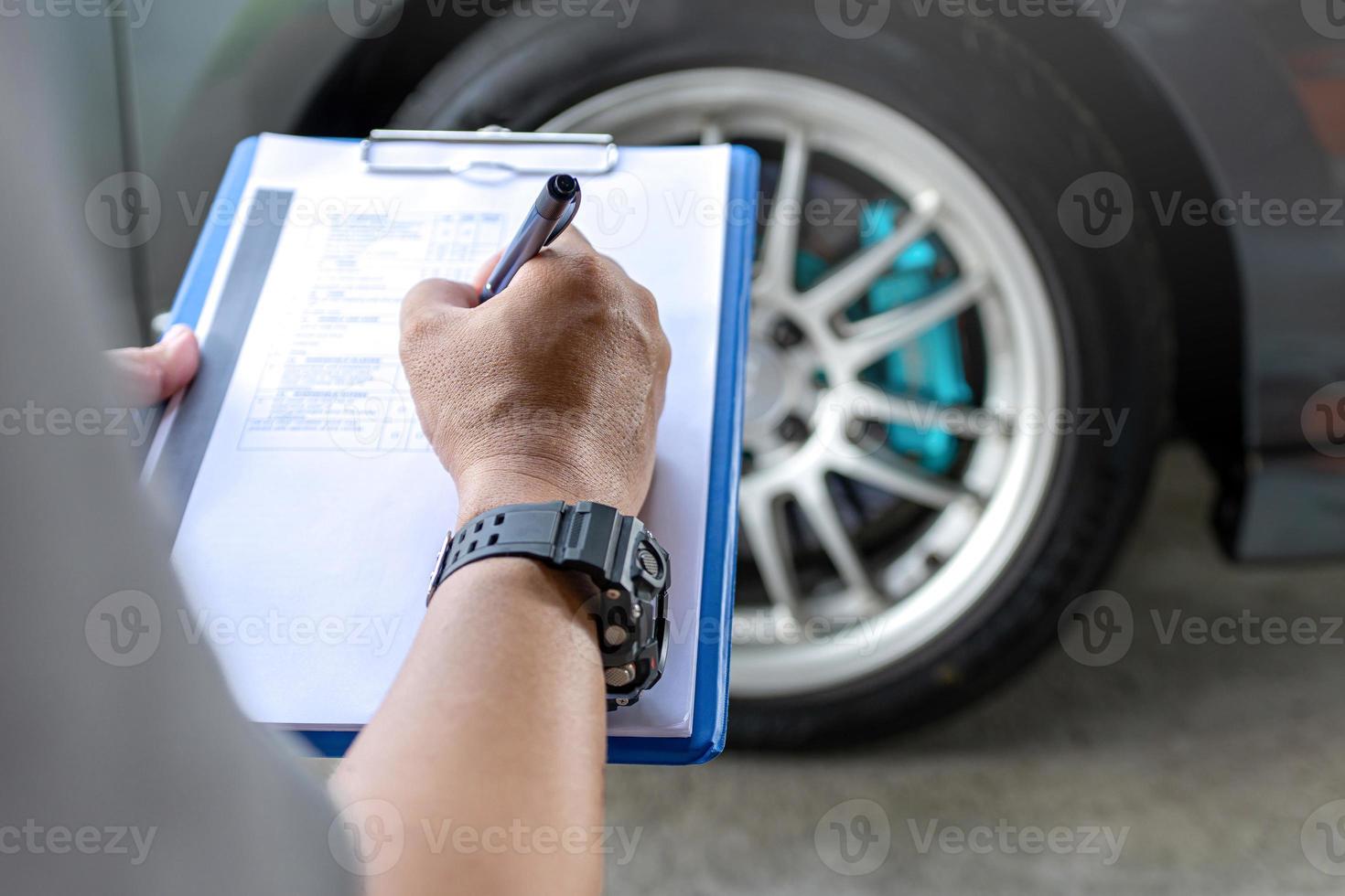 Liste de contrôle d'un homme dans la vérification du cycle de service de la voiture et vérification des données de pression d'air des pneus sur la feuille de contrôle papier concept d'entretien de base de la voiture photo