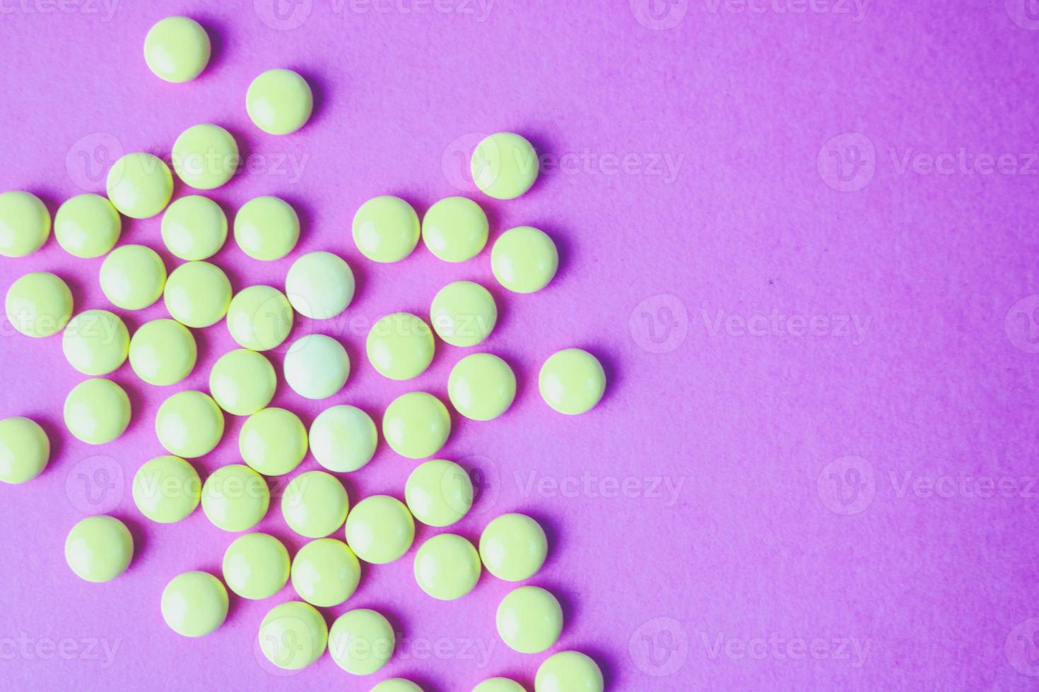 petites pilules rondes pharmaceutiques médicales jaune orange belles, vitamines, médicaments, antibiotiques sur fond violet rose, texture. médecine conceptuelle, soins de santé. mise à plat, vue de dessus photo