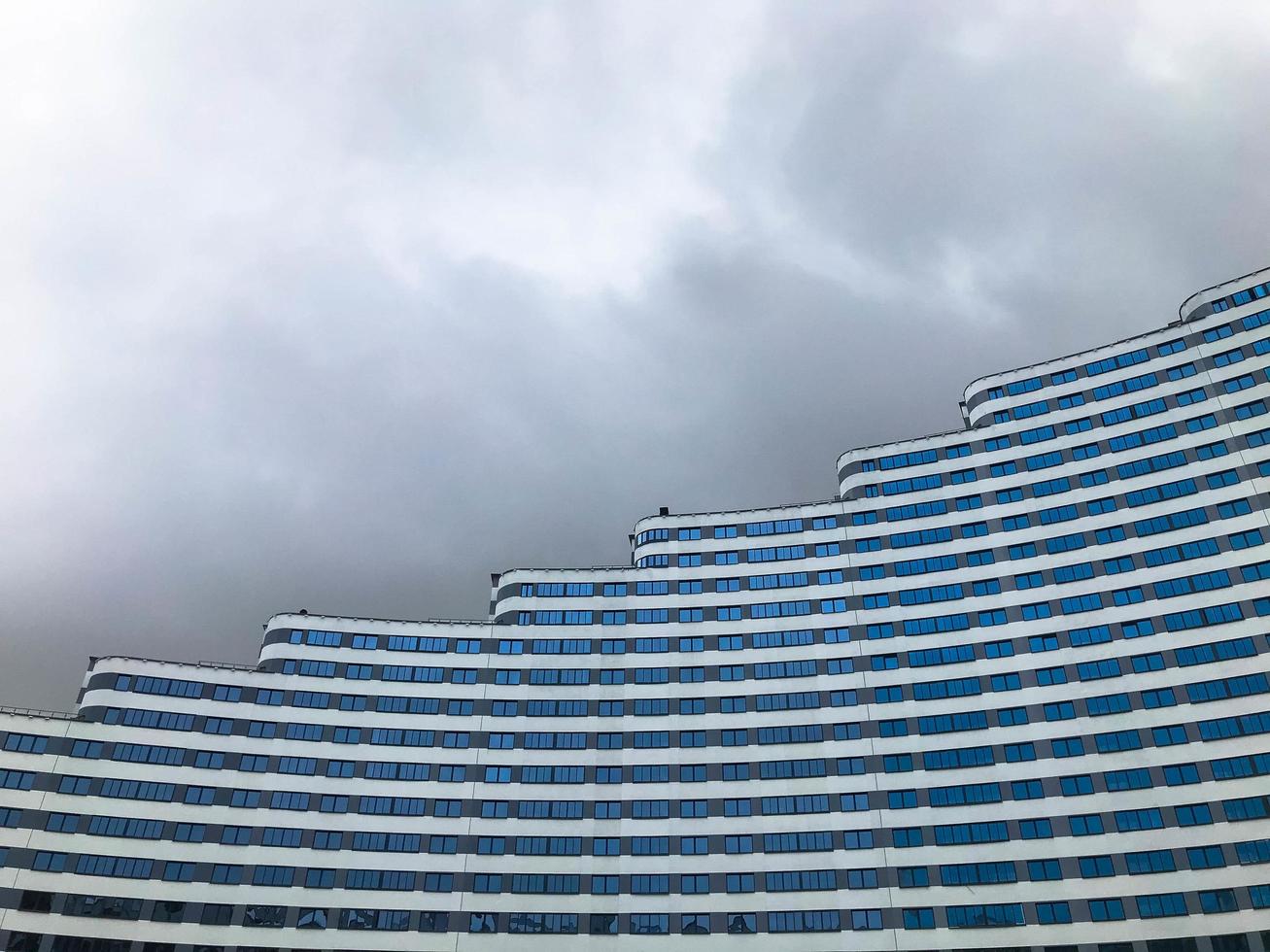 paysage urbain sur fond de ciel nuageux. maison de différentes hauteurs, avec des rouleaux sur le toit, taille de bâtiment non uniforme. bâtiment en forme de vague. au centre ville en bleu et blanc photo