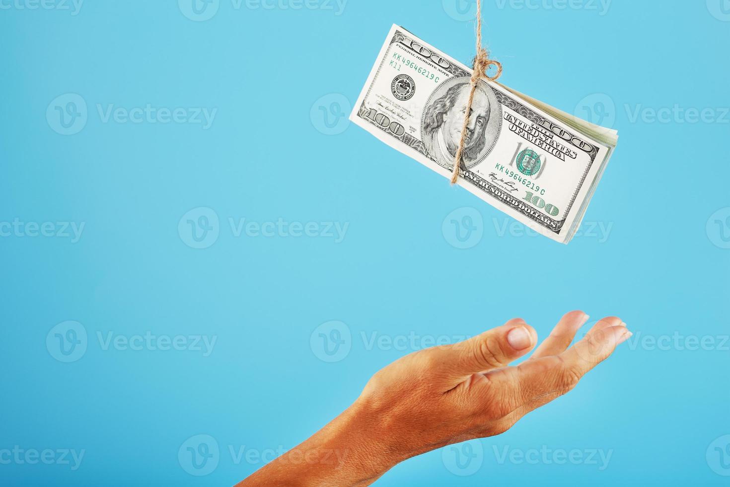 la paume tend la main vers l'argent suspendu à une corde, sur fond bleu. photo
