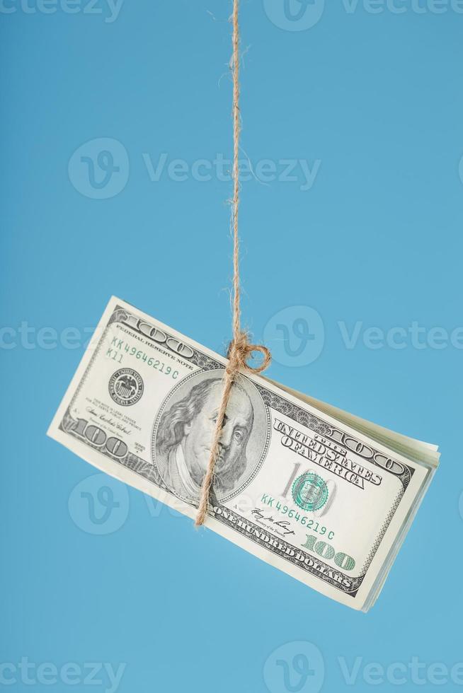 les dollars sont attachés sur une corde, sur un fond bleu. isoler, espace libre. photo