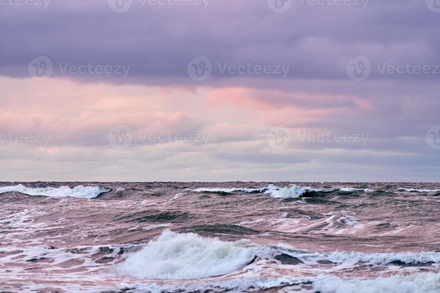 ciel nuageux violet et mer bleue avec des vagues écumantes, paysage marin photo