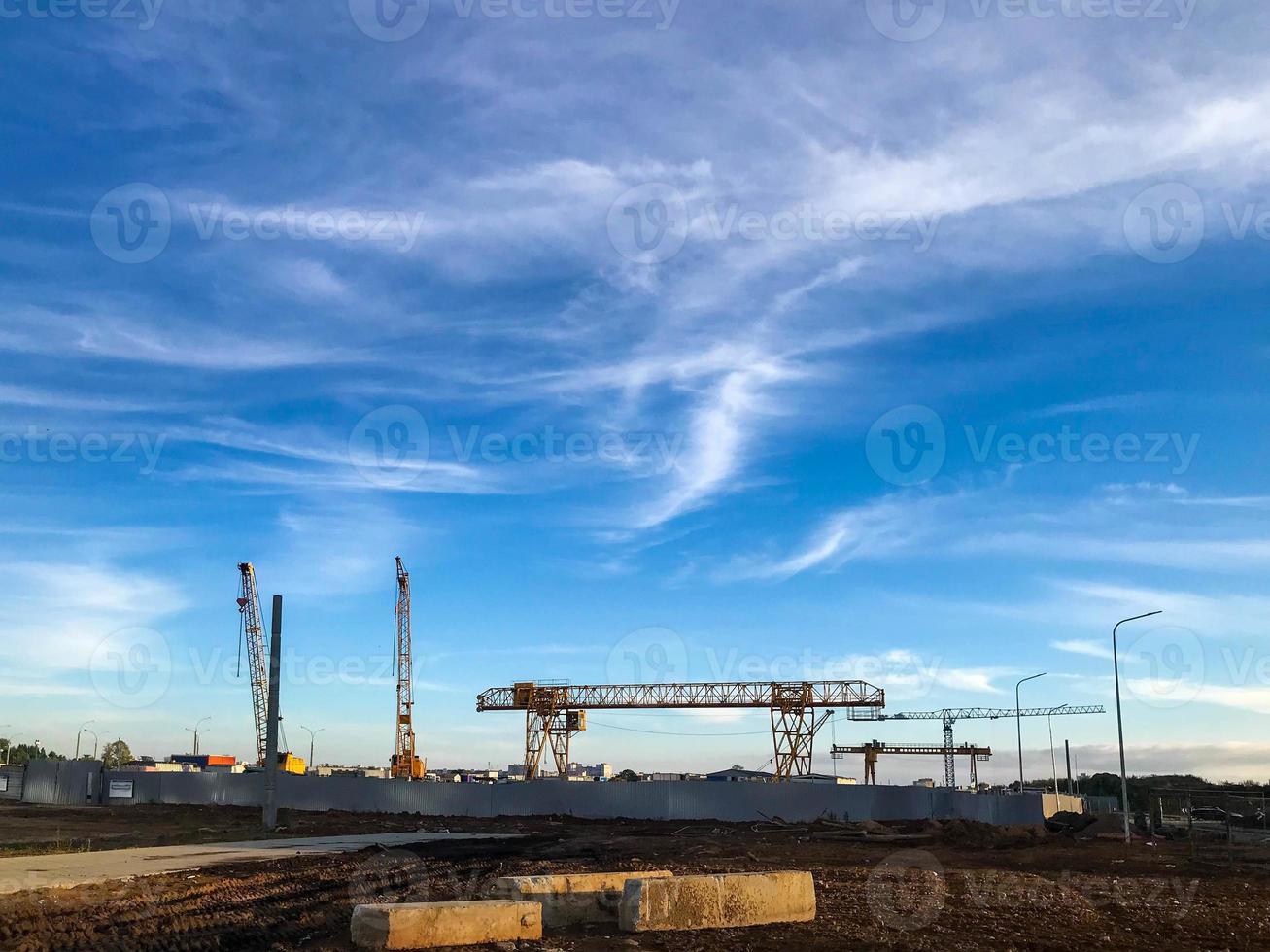 les grues de construction se tiennent sur fond de ciel bleu nuageux. chantier de construction, équipement de creusement de tunnel. grue à portique jaune pour le transport de matériaux lourds en béton photo