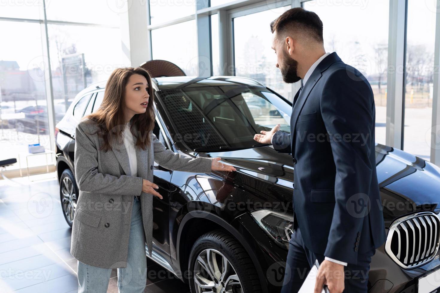 jeune femme acheteuse se disputant dans un concessionnaire automobile avec un consultant, le concept d'achat d'une voiture en location photo
