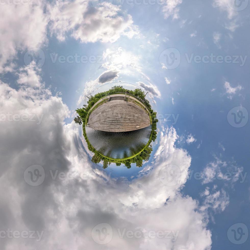 petite planète dans un ciel couvert bleu avec de beaux nuages avec transformation du panorama sphérique à 360 degrés. vue aérienne abstraite sphérique. courbure de l'espace. photo