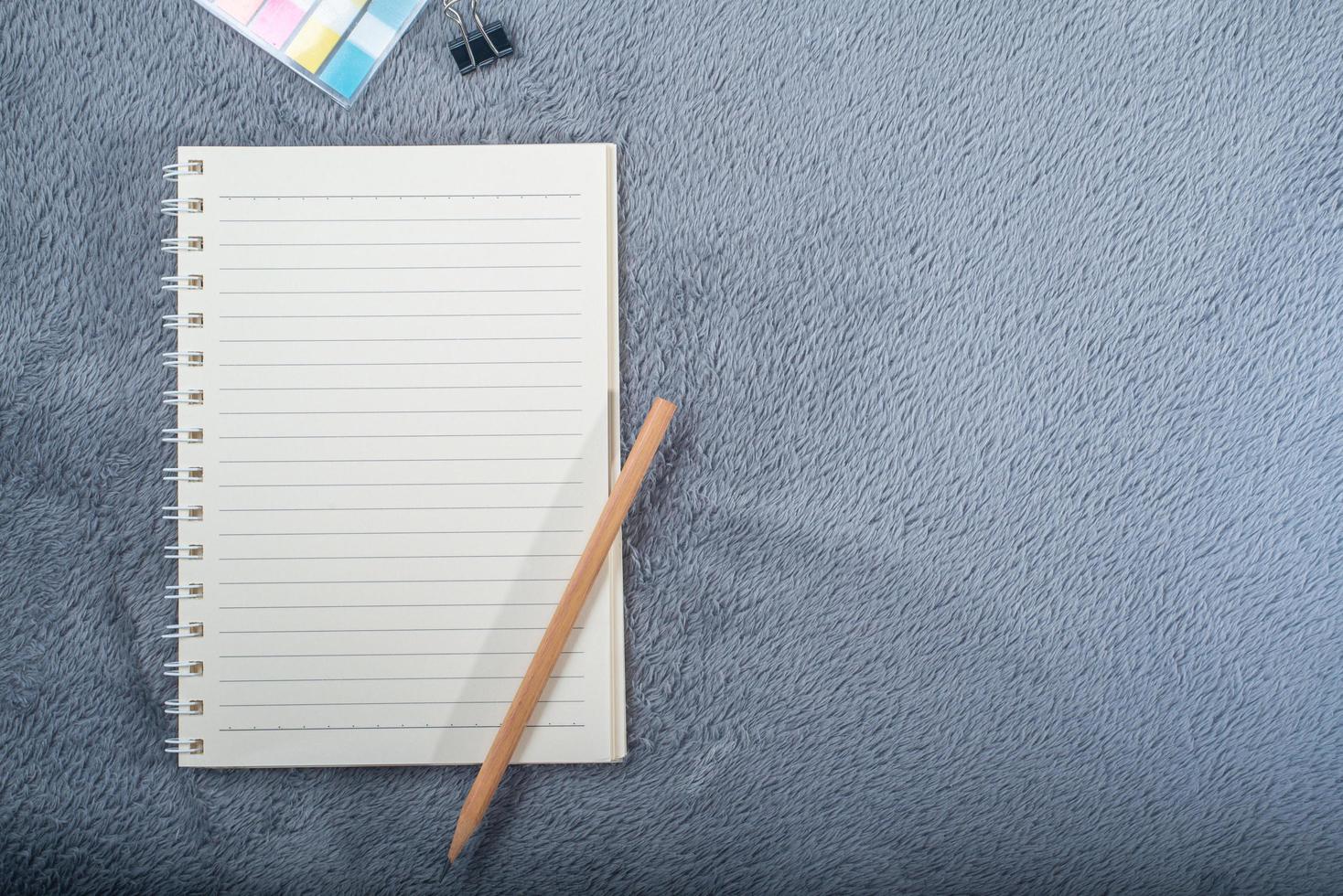 image vue de dessus d'un cahier avec un crayon, une mini note de papier colorée et un trombone sur un tapis gris photo