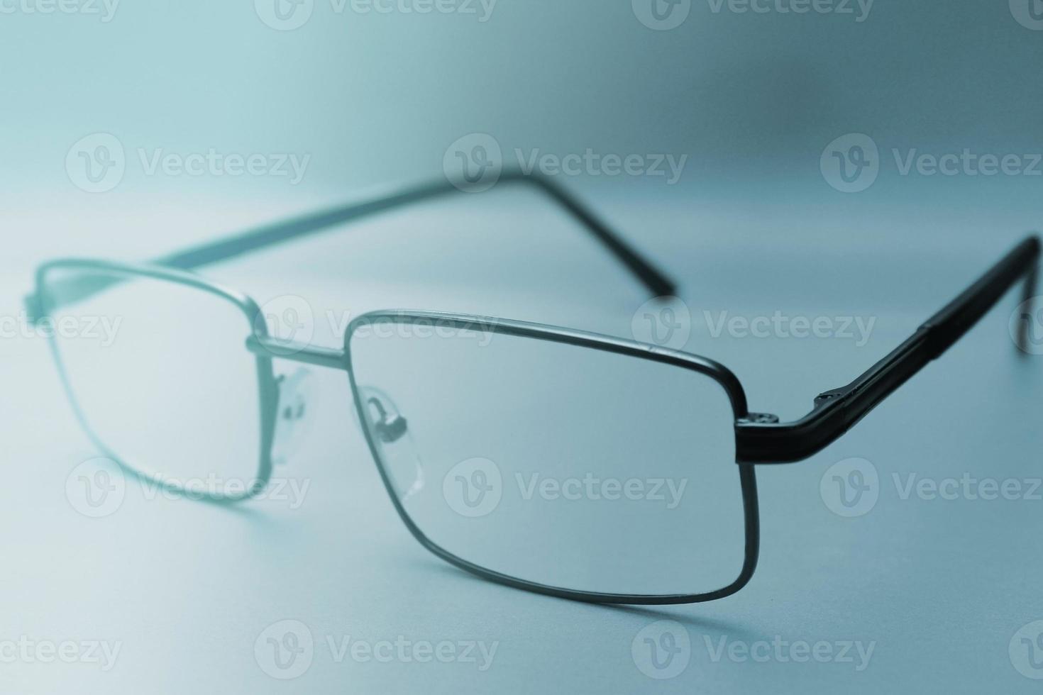 lunettes dans un cadre noir sur fond bleu avec espace de copie. journée mondiale de la vue. mise au point au premier plan. arrière-plan flou photo